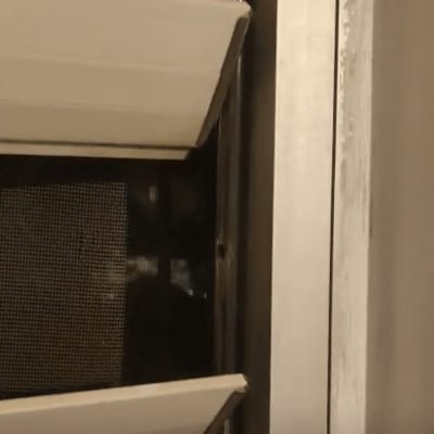 תריסים לבנים מותקנים על חלון עם מסגרת מתכת.