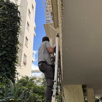 אדם על סולם מתקין מערכת מיזוג אוויר