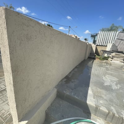 קיר בטון חיצוני עם צינור ירוק על הקרקע