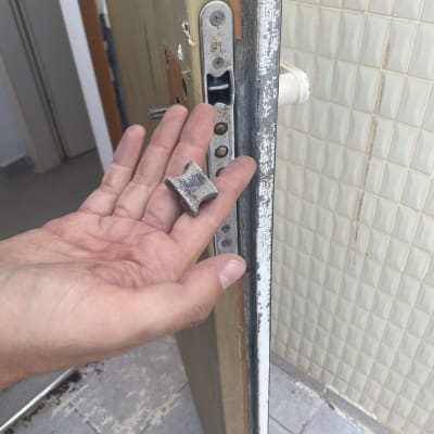 יד מחזיקה חלק מתכת ליד מנעול דלת פתוחה