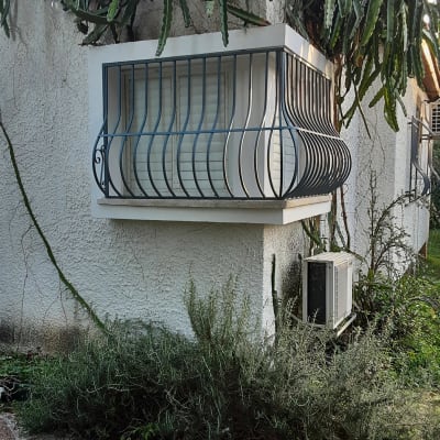 חלון עם סורגי מתכת מעוקלים על קיר חיצוני