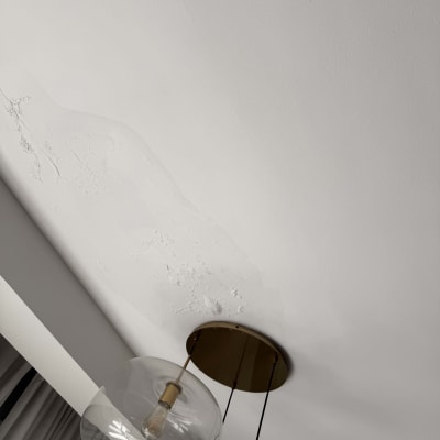 תקרה עם סימני רטיבות ליד מנורה תלויה