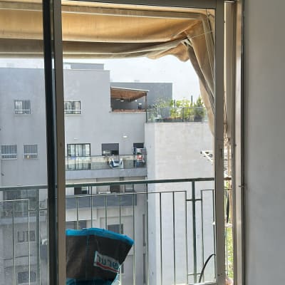 חלון זכוכית עם מסגרת מתכת ומרפסת ברקע