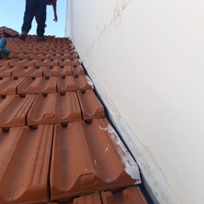 עובד על גג רעפים אדומים ליד קיר לבן