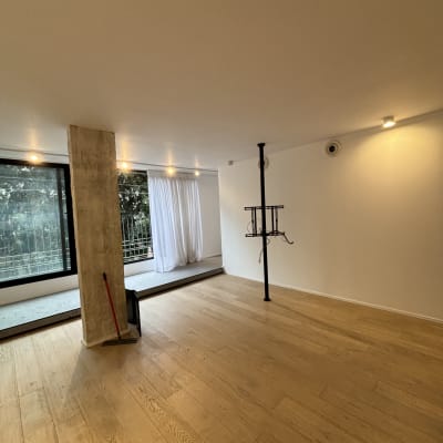 חדר עם רצפת עץ, עמוד בטון ומטאטא בפינה