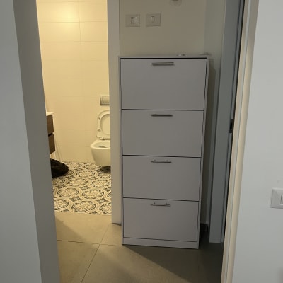 ארון לבן עם ידיות מתכת ליד חדר אמבטיה