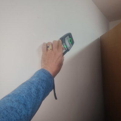 יד מחזיקה מכשיר מדידה על קיר לבן