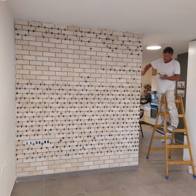 אדם על סולם מתקין אריחים על קיר