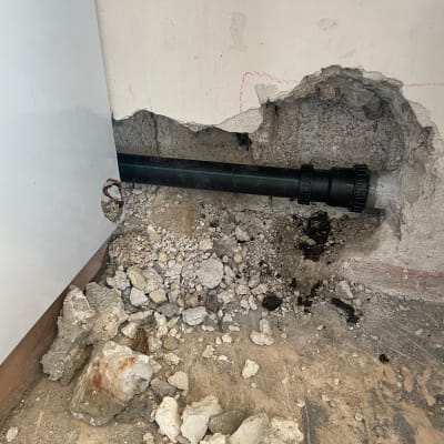 צינור מים בקיר עם אבנים שבורות מסביב