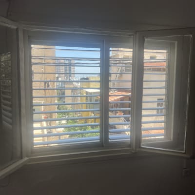 חלון עם תריסי אלומיניום ונוף עירוני ברקע