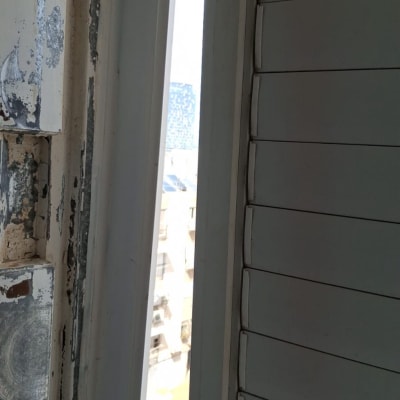חלון עם תריסים וקיר מתקלף