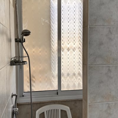 חלון אלומיניום במקלחת עם כיסא פלסטיק