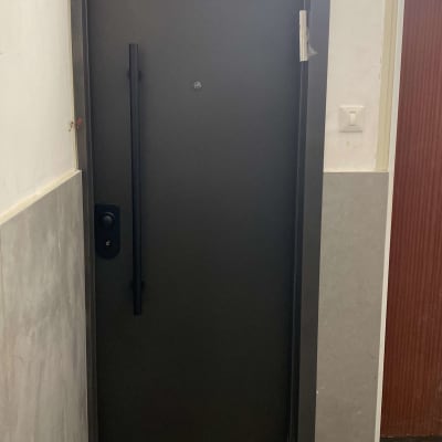 דלת מתכת כהה עם ידית ארוכה ופס דבק