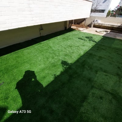דשא סינתטי ירוק בחצר עם צללים על הקרקע