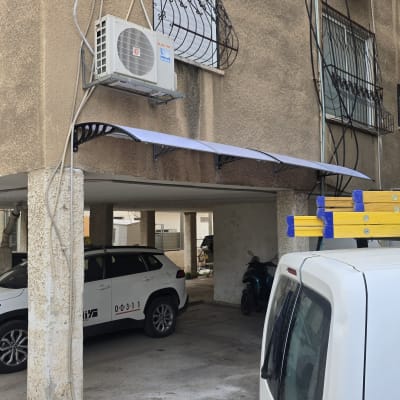 סולם צהוב על רכב לבן ליד בניין עם מזגן