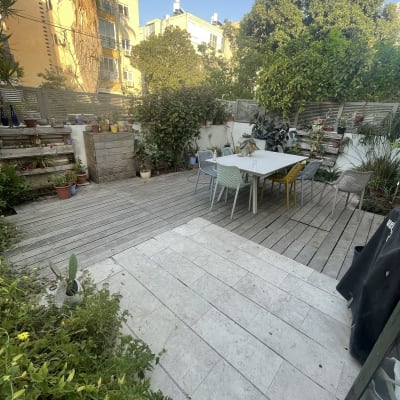 עציצים על מדפים מעץ בגינה, שולחן וכיסאות צבעוניים