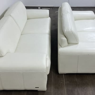 שתי ספות עור לבנות נקיות על רצפת עץ כהה