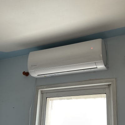 מזגן לבן מותקן על קיר מעל חלון