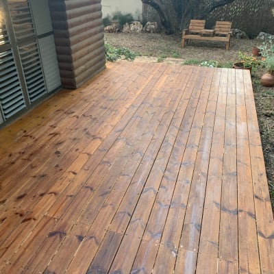 דק עץ בגינה עם ספסל ועץ ברקע