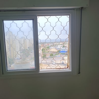 חלון עם סורגים ונוף עירוני ברקע