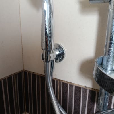 ברז מקלחת עם צינור מים על קיר אריחים