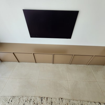 ארון עץ חום מתחת לטלוויזיה על קיר לבן