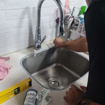 אדם עובד ליד כיור עם כלים וחומרי עבודה