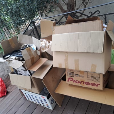 ערימת ארגזי קרטון ארוזים במרפסת כחלק מתהליך אריזה ומעבר דירה