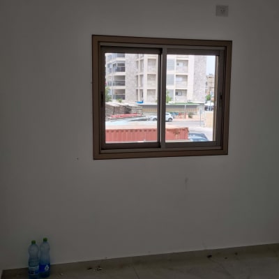 חלון אלומיניום עם מסגרת חומה על קיר לבן