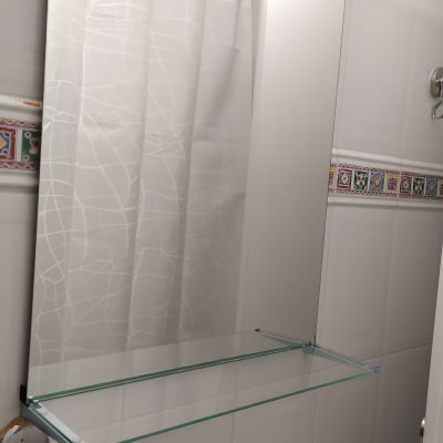 מראה עם מדף זכוכית וברז בחדר אמבטיה