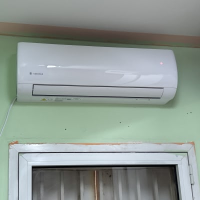 מזגן קיר לבן מותקן מעל חלון