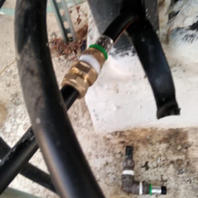 צינורות שחורים עם מחברים מתכתיים על רקע בטון