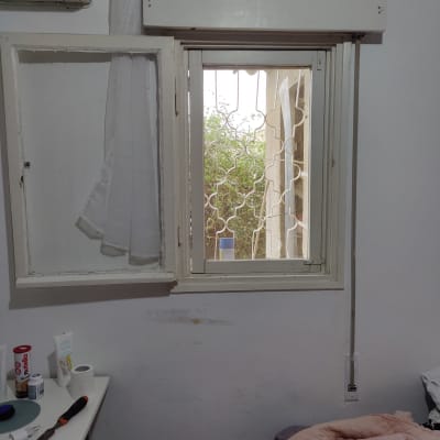 חלון עם תריסים פתוחים ומסגרת לבנה