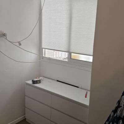 מזגן מותקן על קיר מעל שידה לבנה