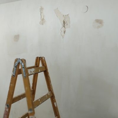 סולם עץ ליד קיר עם קילופי צבע
