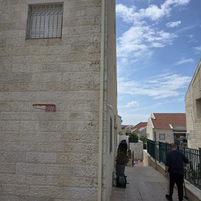 אדם מטאטא שביל ליד בניין אבן עם סל כדורסל