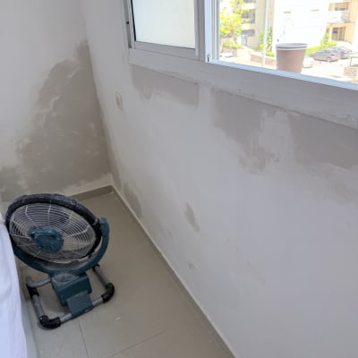 קיר עם תיקוני צבע ומאוורר קטן בחדר