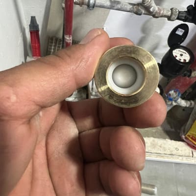 יד מחזיקה חלק מתכת ליד צינור מים