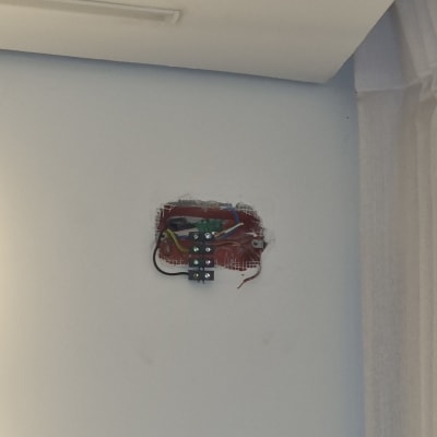 חוטי חשמל מחוברים לקופסת חיבורים בקיר