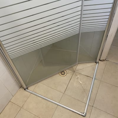 דלת מקלחת מזכוכית עם פסי מתכת ורצפת קרמיקה