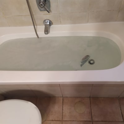 אמבטיה מלאה במים עם ברז ומקלחת