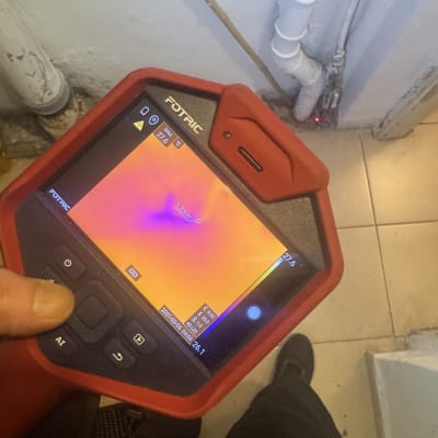 מד חום תרמי מציג תוצאות על צינור קיר