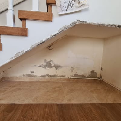 קיר מתקלף מתחת למדרגות עם סימני רטיבות