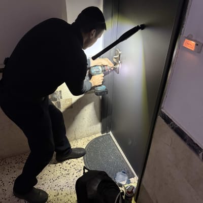 אדם משתמש במקדחה על מנעול דלת.