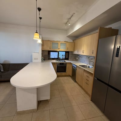 מטבח נקי עם אי, כיור ומקרר.