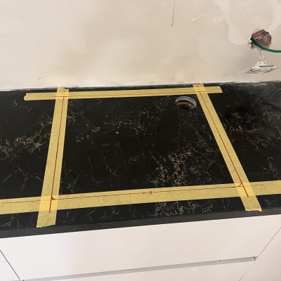 משטח שיש כהה עם סרט מדידה צהוב ומדבקות.