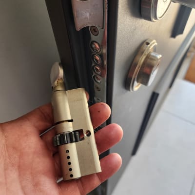 יד מחזיקה צילינדר מנעול מול דלת פתוחה