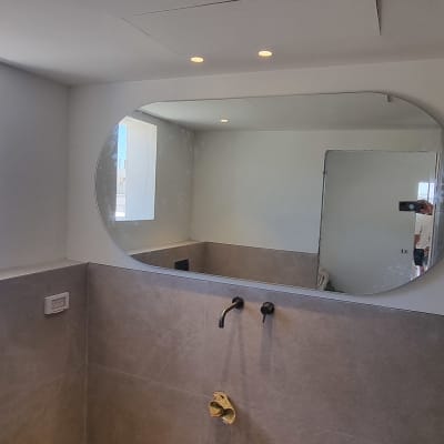 מראה עגולה גדולה תלויה על קיר בחדר אמבטיה