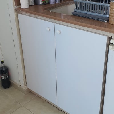 מטבח עם ארונות לבנים וכיור נירוסטה