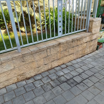 גדר מתכת אפורה על קיר אבן חום